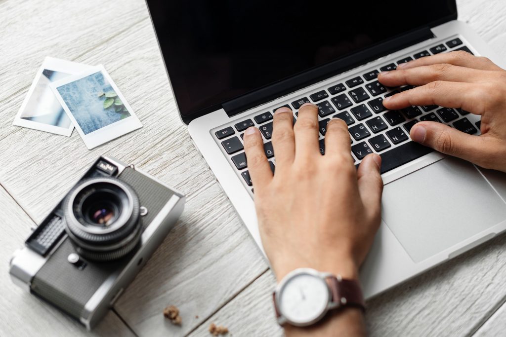 Slow tech: person typing on laptop with polaroid photos